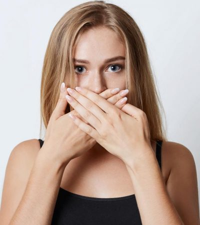 bad breath, woman covering her mouth