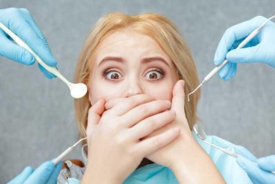 Dental anxiety, patient covering her mouth at the dentist, fear of the dentist