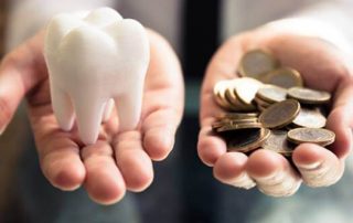 Cost of avoiding the dentist, hand holding tooth and hand holding coins