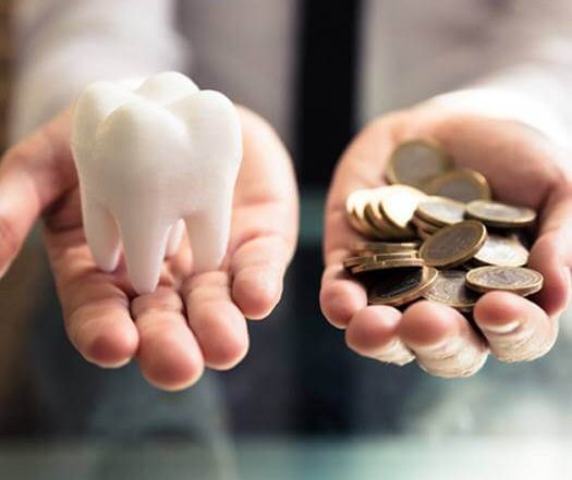 Cost of avoiding the dentist, hand holding tooth and hand holding coins